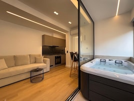 Una sala de estar moderna con sofá, mesa de centro, zona de cocina y bañera de hidromasaje.