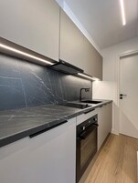 Una cocina moderna con encimera de mármol negro, horno empotrado y una campana extractora negra elegante.