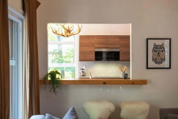 A modern kitchen with wooden cabinets, a built-in oven, and a window overlooking greenery. - Cloud Ten-Close to ski resort (Calabogie)