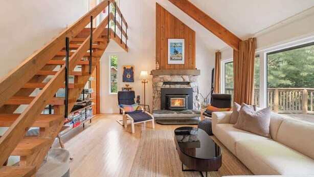 A living room with a fireplace, a sofa, a chair, a coffee table, and a staircase.