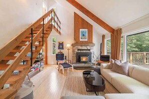 A living room with a fireplace, a sofa, a chair, a coffee table, and a staircase.