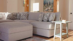A living room with a sectional sofa, a small table, and a painting on the wall. - Mountain View Chalet (Calabogie)