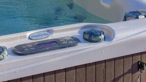 A hot tub with a control panel, surrounded by a wooden deck and snow-covered ground. - Mountain View Chalet (Calabogie)