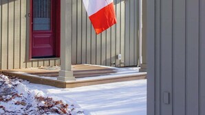 A house with a red door, a porch, and a Canadian flag. - Mountain View Chalet (Calabogie)