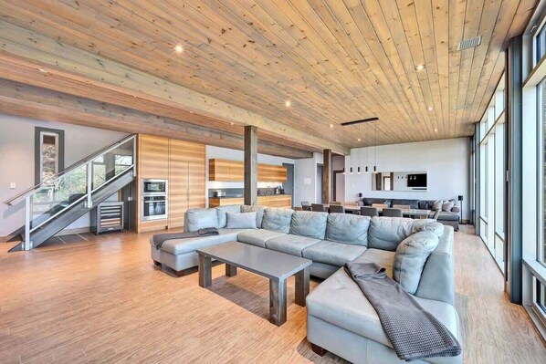 A modern living room with a sectional sofa, a coffee table, and a staircase leading to an upper level.