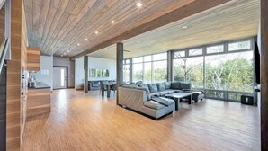 A spacious living area with a wooden ceiling, large windows, and a modern sofa. - Lake House Wood Sauna & Hot Tub (Portland)