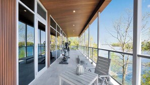 A covered outdoor area with exercise equipment, seating, and a view of a body of water. - Lake House Wood Sauna & Hot Tub (Portland)