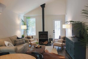A living room with a fireplace, a sofa, chairs, a coffee table, and a cabinet.