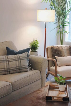 A living room with a sofa, a lamp, a coffee table, and a potted plant.