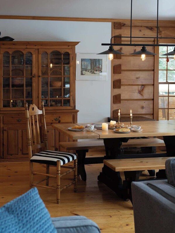 Un coin repas chaleureux, avec des meubles en bois, un grand meuble et un luminaire suspendu.