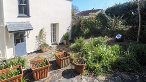 Een wit huis met een pannendak, een stenen pad en potplanten.