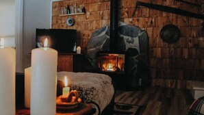 A cozy room with a stone fireplace, candles, and a television. - Loggers Lodge an Anglers Retreat (Calabogie)