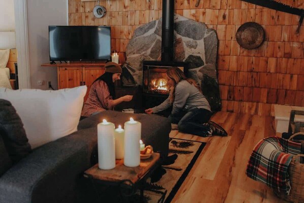 Una sala acogedora con chimenea de piedra, un televisor y un sofá cómodo.
