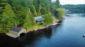 A lakeside cabin with a dock, surrounded by dense forest.