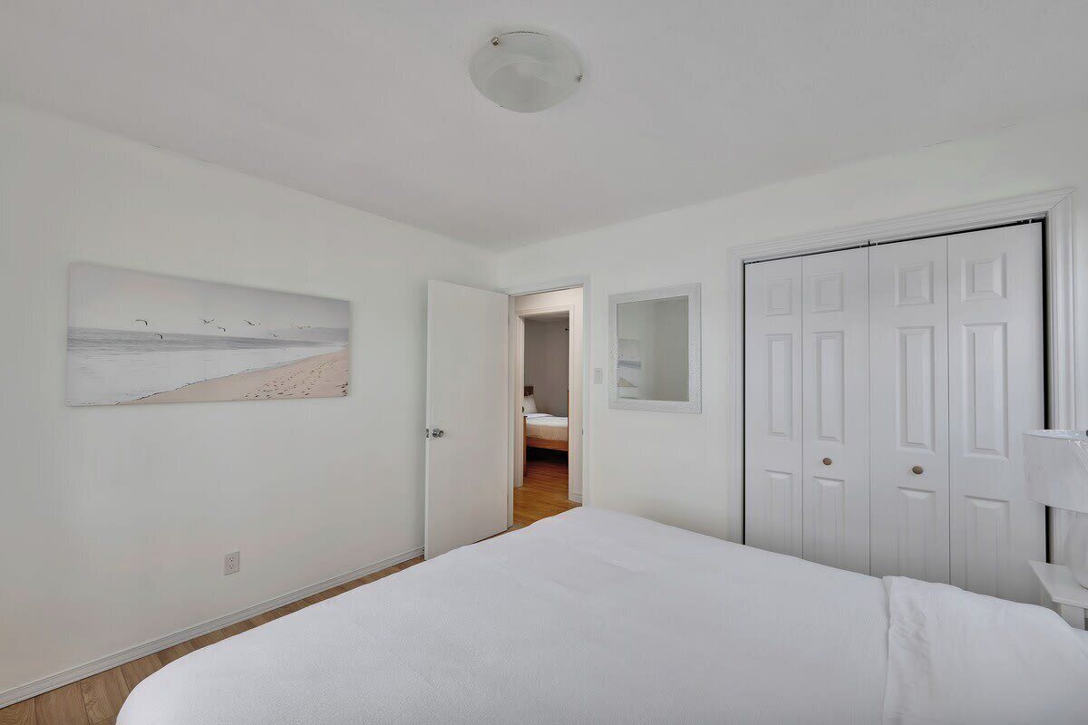 A bedroom with a bed, a door, a mirror, and a painting on the wall.