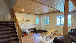 Een ruime loft met een houten trap, een leren zwarte bank, een houten plafond en uitzicht op het omliggende landschap.