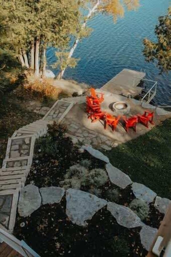 A patio with stone steps, a fire pit, and red chairs.