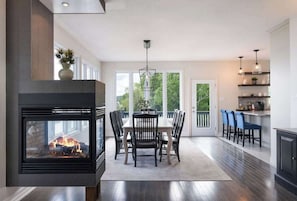 A modern kitchen with a fireplace, dining area, and bar.