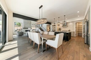 Una cucina moderna con zona pranzo, pavimento in legno e illuminazione a sospensione.