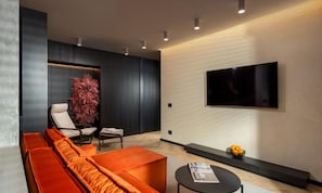Una sala de estar moderna con un sofá, un sillón y un televisor de pantalla plana montado en la pared.