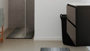 Un baño con ducha, inodoro, lavabo y un estante con artículos de tocador.