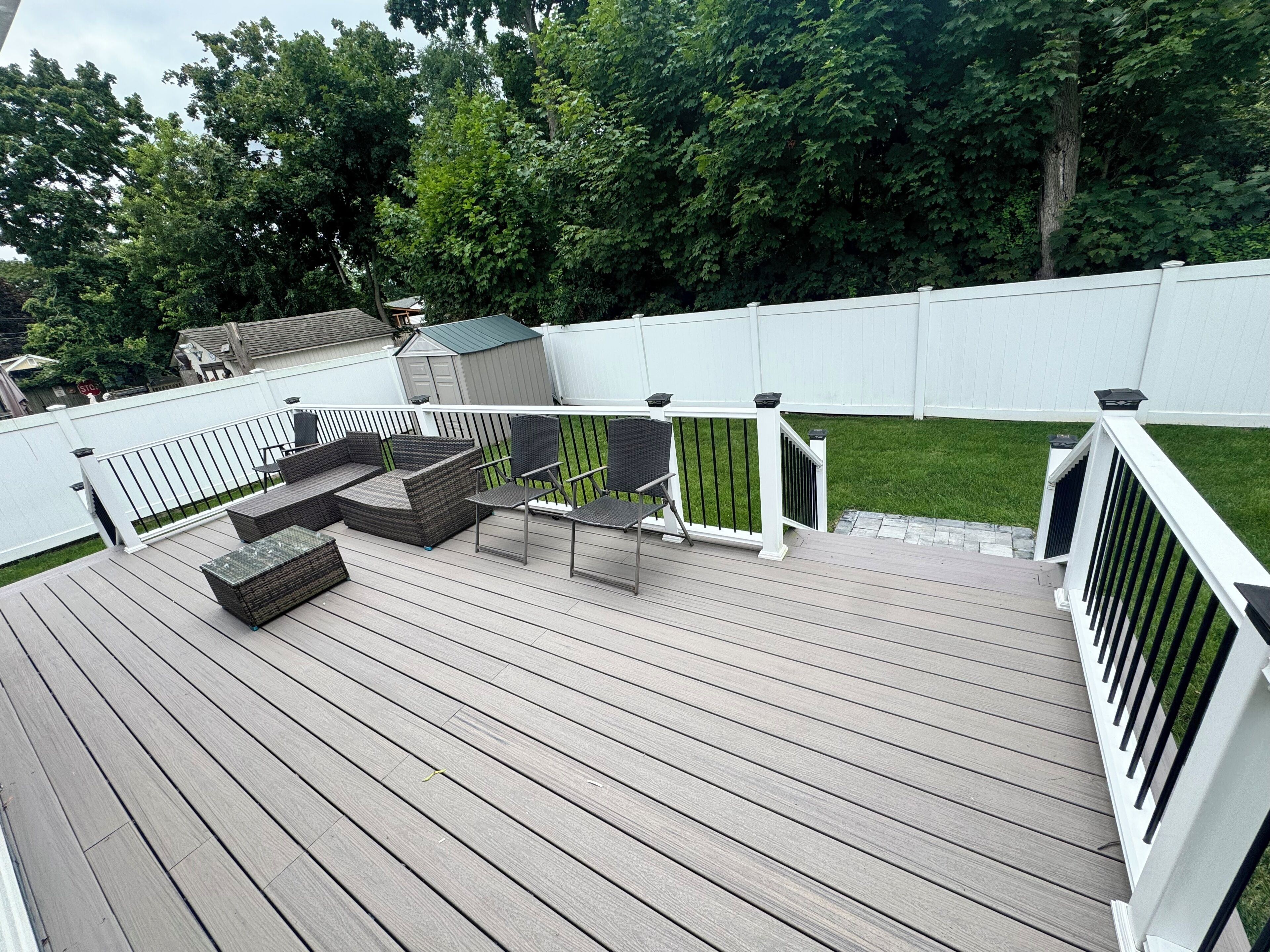 Een houten terras met tuinmeubilair en een witte schutting.