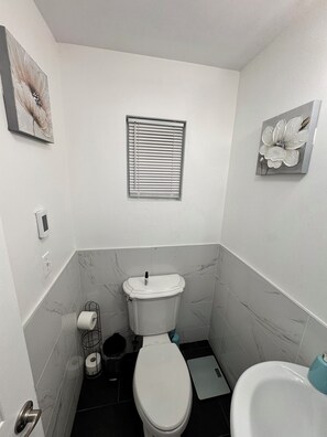 A compact bathroom with a toilet, bidet, and a small window.