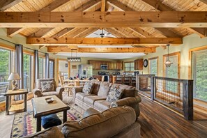 Ein geräumiges Wohnzimmer mit Holzbalkendecke, einer Essecke und einer Küche.