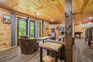 A wooden cabin interior with a pool table, comfortable seating, and arcade games. - New! MTN Views! Hot Tub + Theater*5 Mins to GBurg (Gatlinburg)