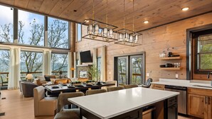Une cuisine moderne dotée d’un îlot central, de meubles en bois et d’une grande fenêtre donnant sur un paysage magnifique.