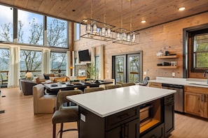 Una cocina moderna con una isla central, armarios de madera y un amplio ventanal con vistas panorámicas.
