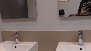 A bathroom with two white sinks, a mirror above, and a towel rack. - The Empire Inn (Serowe)