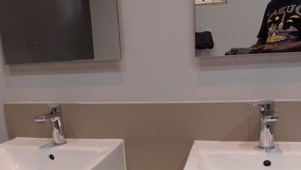 Une salle de bain avec deux lavabos blancs, un miroir au-dessus et un porte-serviettes.