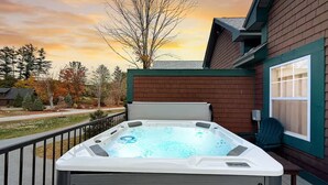 A hot tub on a deck with a view of trees and a house in the background. - Cranmore Heights | Luxe, Hot Tub, Walk Downtown (North Conway)