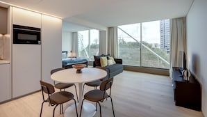 A modern living room with a sofa, a dining table with chairs, a TV, and a large window with a view. - Areeiro Vision Studio by Homing (Lisbon)