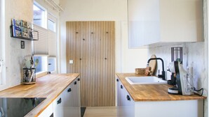 A modern kitchen with wooden countertops, a built-in oven, and a window with blinds. - The Kingfisher is a comfortable ground-floor bungalow with fenced garden, wood stove and fully equipped kitchen. Near the beach, dunes and forest of Schoorl, Petten and Bergen. Perfect for families and dog lovers. (Dirkshorn)
