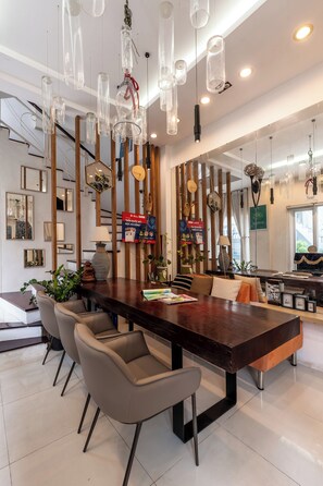 Uma sala de jantar moderna com uma mesa de madeira, cadeiras e luminárias pendentes.