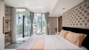 A hotel room with a large bed, a glass door leading to a balcony, and a view of the outside. - Cozrum - Idea Apartment (Ho Chi Minh City)