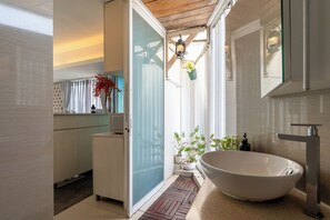 Un baño moderno con una bañera independiente, cabina de ducha con mampara de vidrio y un pequeño lavabo.