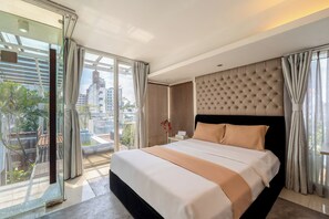 Ett modernt hotellrum med en stor säng, en glasdörr som leder ut till en balkong och utsikt över staden.