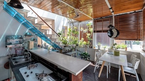 A modern kitchen with a gas stove, a sink, and a countertop. There is a staircase with a blue railing leading to an upper level. - Cozrum - Idea Apartment (Ho Chi Minh City)