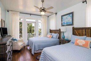Une chambre avec deux lits, un ventilateur de plafond, une télévision et une tête de lit en bois.