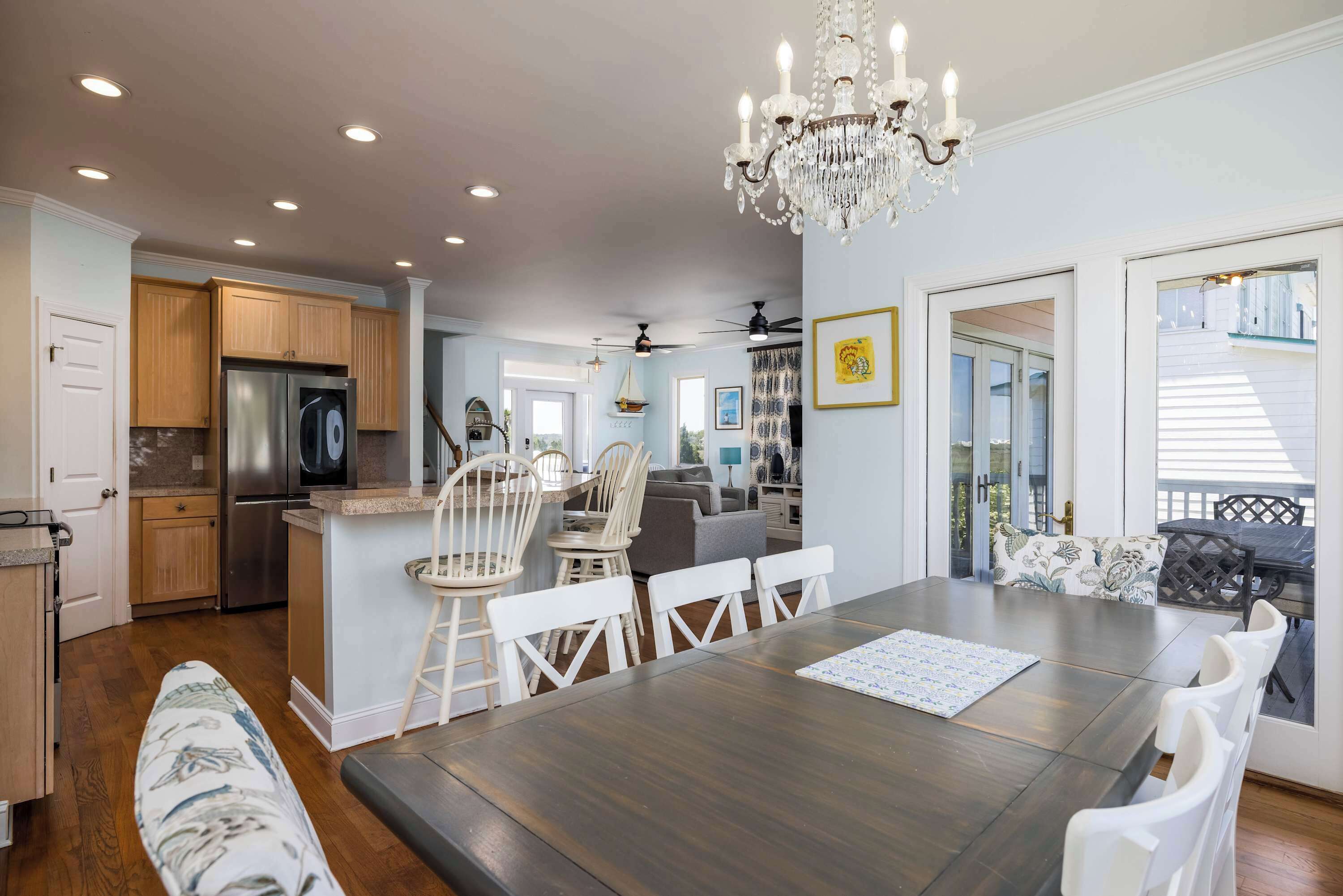 A spacious kitchen with a refrigerator, wooden cabinets, and a dining area with a table and chairs.