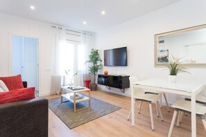 A modern living room with a sofa, a coffee table, a TV, a dining table, and chairs. - Great 4 bedroom Apartment Sagrada Familia (Barcelona)