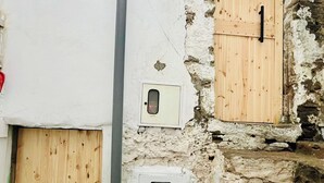 Ein rustikales Gebäude mit zwei Holztüren, einer Steinwand und einer Metallrohrleitung.