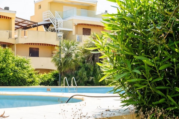Un espace piscine offrant une vue dégagée sur un immeuble doté de balcons et d’un escalier.