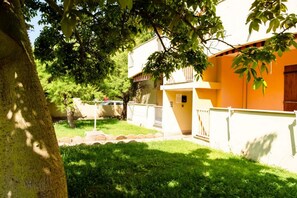 A building with a yellow facade, a tree in the foreground, and a grassy area in the background. - A comfortable 65 square meters apartment, perfect for six people, located on the first floor of a building without an elevator within a residential complex.The property is located in Alghero and enjoys an excellent location, close to the sea and several  (Alghero)