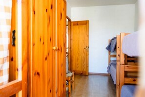 Ein Zimmer mit Holzmöbeln, darunter ein Kleiderschrank, eine Sitzbank und ein Etagenbett.