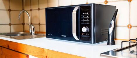 Un microondas Samsung sobre una encimera de cocina con un fregadero y armarios de madera.