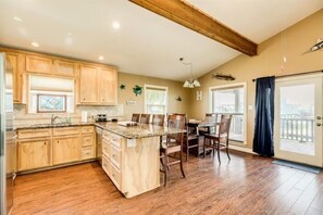 A kitchen with wooden cabinets, a granite countertop island, and a dining area with chairs and a table.